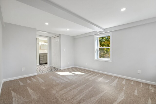 unfurnished room featuring light carpet and beamed ceiling