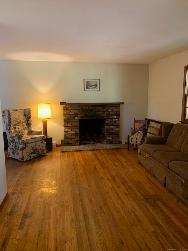 living room with a brick fireplace and hardwood / wood-style floors