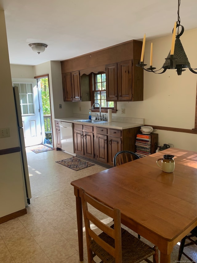 kitchen featuring a healthy amount of sunlight, white appliances, sink, and a chandelier