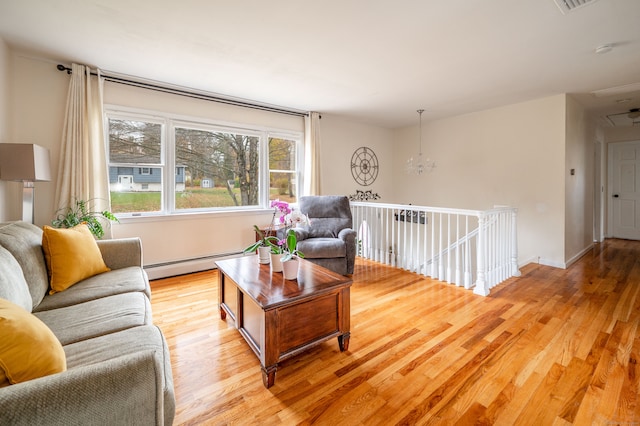 living room featuring baseboard heating, light hardwood / wood-style flooring, and an inviting chandelier