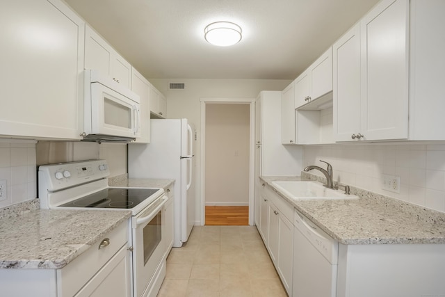 kitchen with white cabinetry, sink, light stone countertops, and white appliances