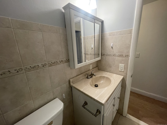 bathroom with vanity, toilet, tile walls, and hardwood / wood-style floors