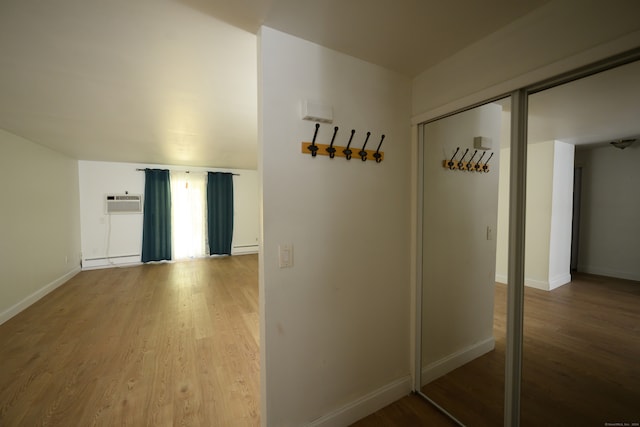 corridor with a baseboard heating unit and hardwood / wood-style floors