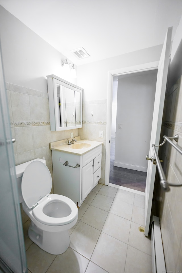 bathroom with a baseboard radiator, toilet, tile walls, vanity, and tile patterned flooring