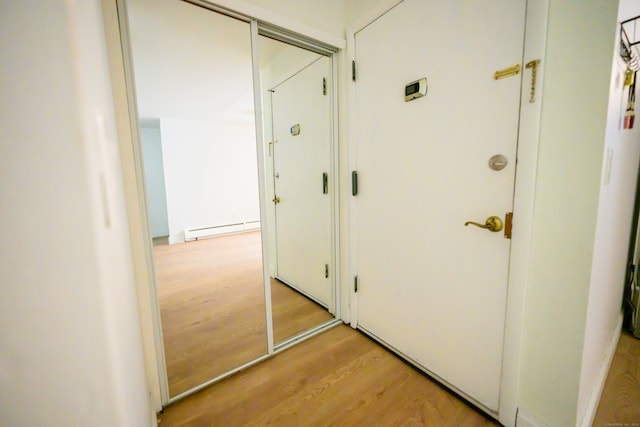 hall with light hardwood / wood-style floors and baseboard heating