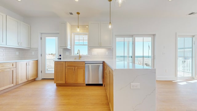 kitchen featuring tasteful backsplash, light stone countertops, stainless steel dishwasher, and white cabinets