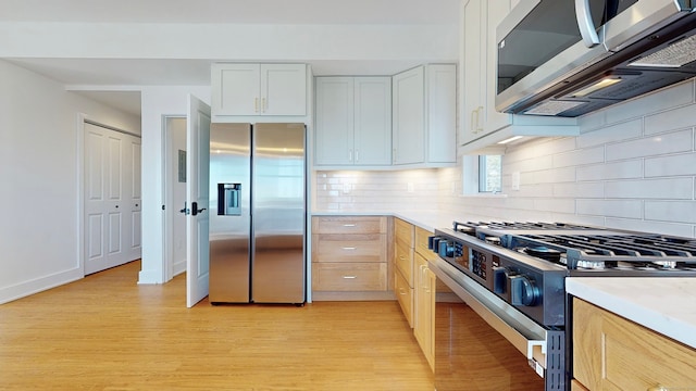 kitchen with appliances with stainless steel finishes, light hardwood / wood-style flooring, light brown cabinets, and white cabinets