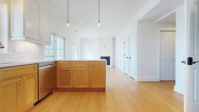 kitchen with decorative backsplash, hanging light fixtures, a large fireplace, light hardwood / wood-style flooring, and dishwasher