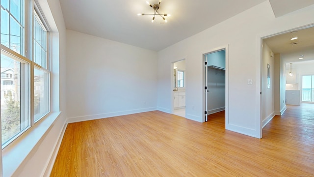 empty room with a notable chandelier and light hardwood / wood-style flooring