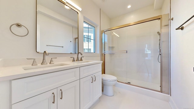 bathroom with vanity, toilet, and a shower with door