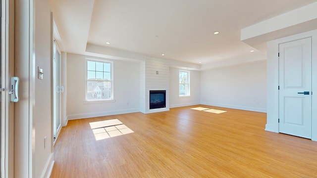 unfurnished living room featuring a large fireplace and light hardwood / wood-style flooring