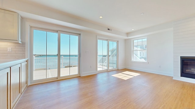 unfurnished living room featuring light wood-type flooring and a large fireplace