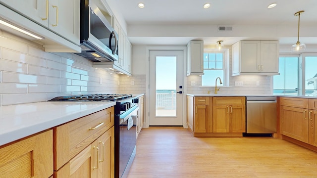 kitchen featuring light wood-type flooring, sink, white cabinetry, appliances with stainless steel finishes, and backsplash