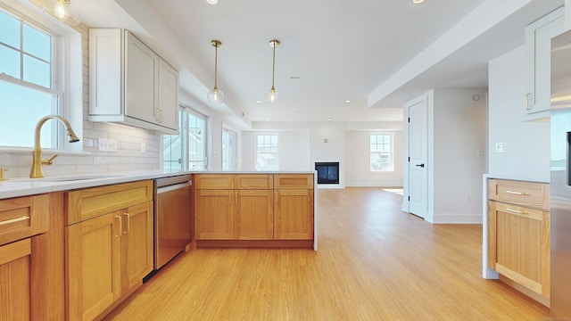 kitchen featuring light wood-type flooring, a large fireplace, sink, dishwasher, and white cabinetry