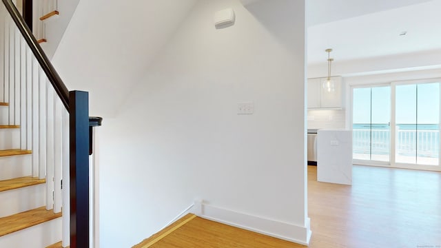 stairway with wood-type flooring, lofted ceiling, and a water view