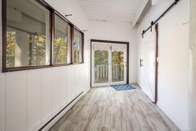 corridor with beamed ceiling, a barn door, light hardwood / wood-style floors, and a baseboard radiator