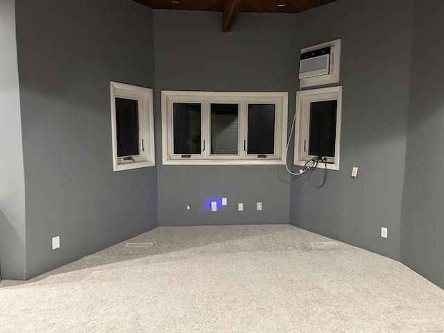 carpeted empty room with beamed ceiling, high vaulted ceiling, and a wall mounted AC