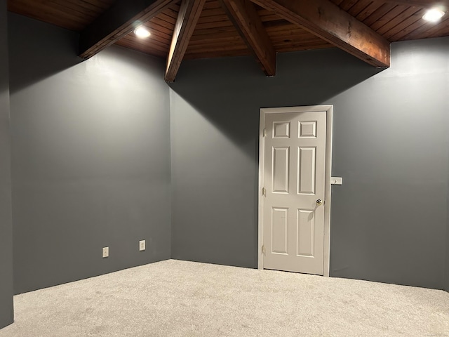 carpeted empty room featuring beam ceiling and wood ceiling