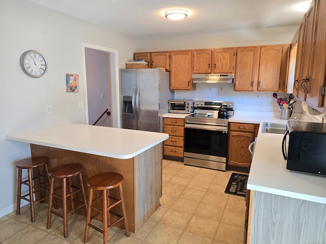 kitchen with backsplash, appliances with stainless steel finishes, and a breakfast bar area