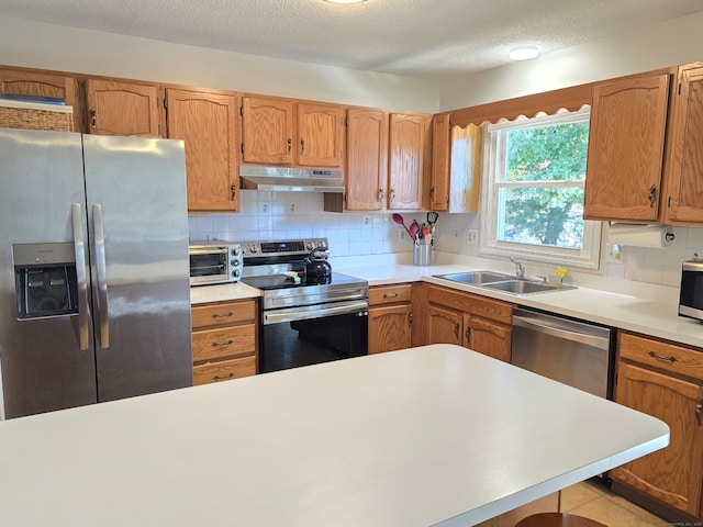 kitchen featuring sink, decorative backsplash, stainless steel appliances, and a textured ceiling