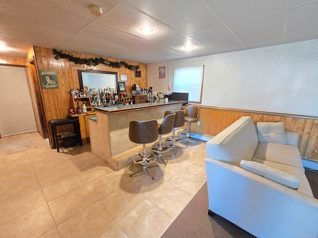 bar with baseboard heating, wooden walls, and light tile patterned floors