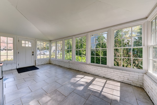 unfurnished sunroom featuring vaulted ceiling and a healthy amount of sunlight