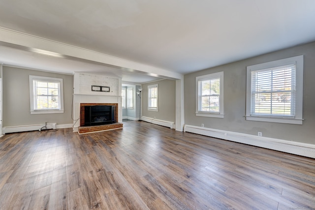 unfurnished living room featuring hardwood / wood-style floors, a healthy amount of sunlight, and a baseboard heating unit