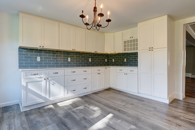 kitchen with decorative light fixtures, light hardwood / wood-style floors, white cabinetry, and decorative backsplash