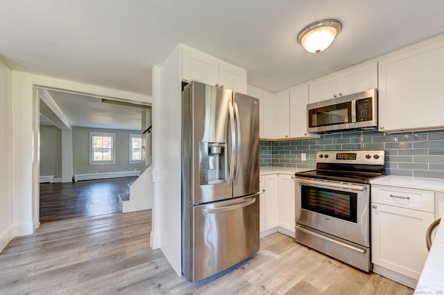 kitchen featuring white cabinets, light hardwood / wood-style flooring, appliances with stainless steel finishes, a baseboard radiator, and decorative backsplash