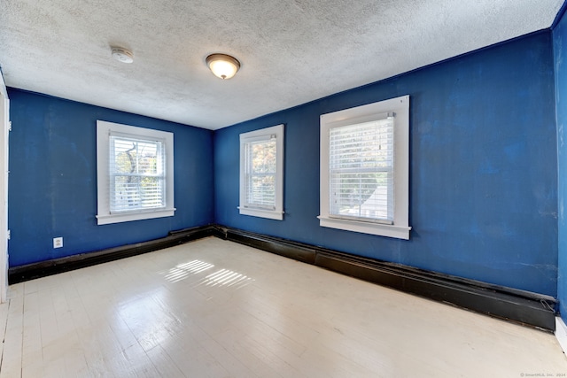 spare room featuring light hardwood / wood-style floors and a textured ceiling