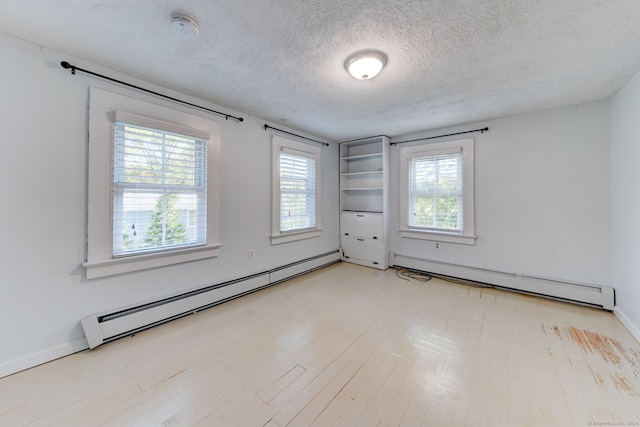 spare room with a textured ceiling, baseboard heating, and light hardwood / wood-style floors