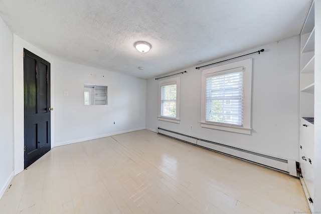 spare room with light hardwood / wood-style floors, a baseboard heating unit, and a textured ceiling