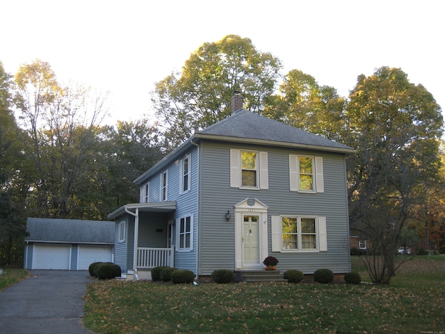 colonial-style house featuring a front yard, a garage, and an outdoor structure