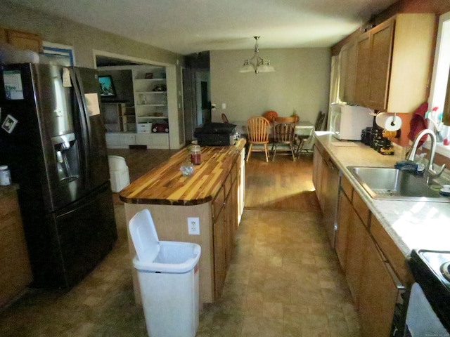 kitchen featuring wood counters, a center island, black fridge, sink, and decorative light fixtures