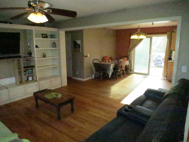 living room featuring hardwood / wood-style flooring and ceiling fan with notable chandelier