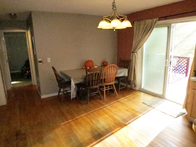 dining space with wood-type flooring and an inviting chandelier