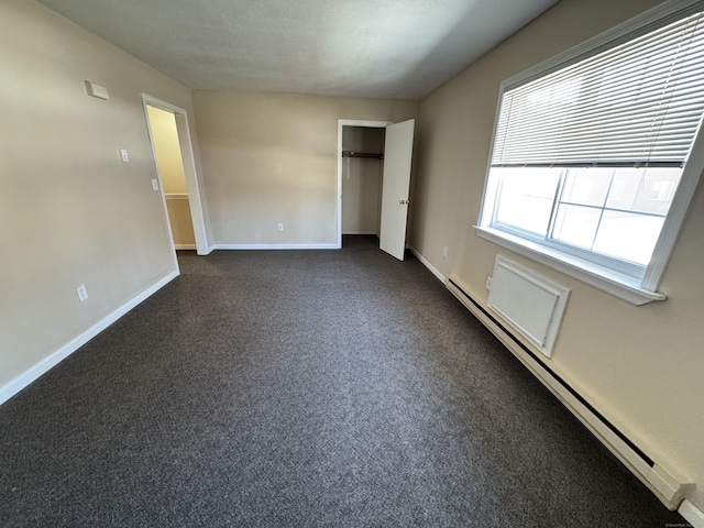 empty room with dark colored carpet, baseboards, and a baseboard radiator