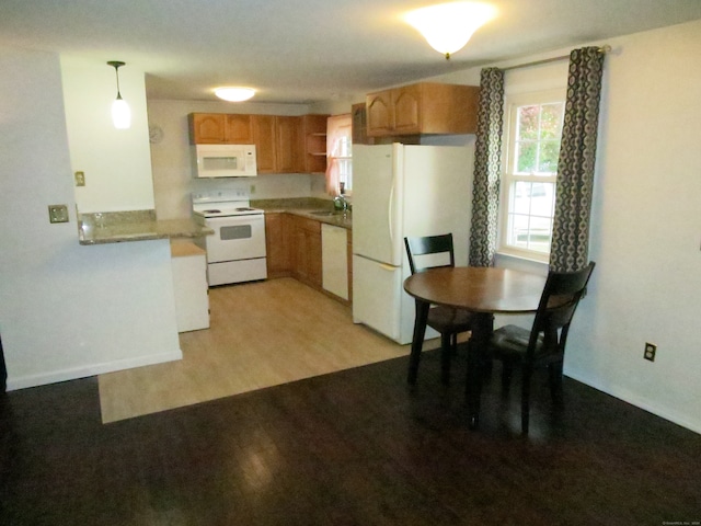 kitchen featuring white appliances, light hardwood / wood-style flooring, pendant lighting, and sink