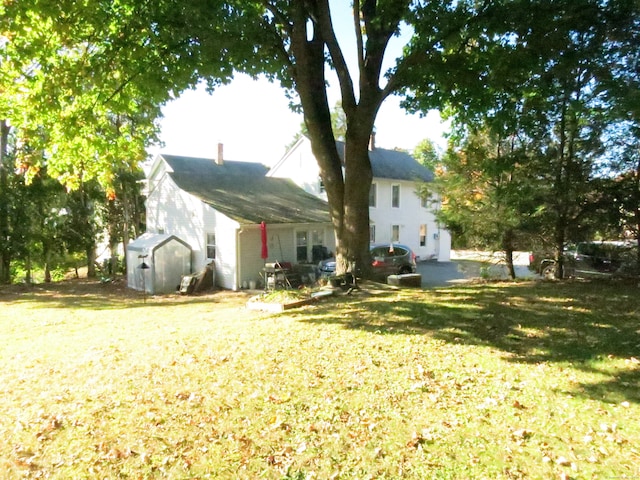 rear view of property featuring a storage shed and a lawn