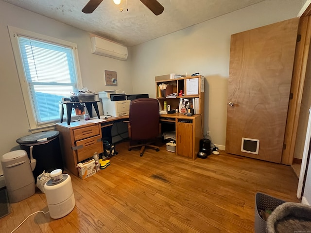 home office featuring a textured ceiling, a wall mounted air conditioner, ceiling fan, and light hardwood / wood-style flooring