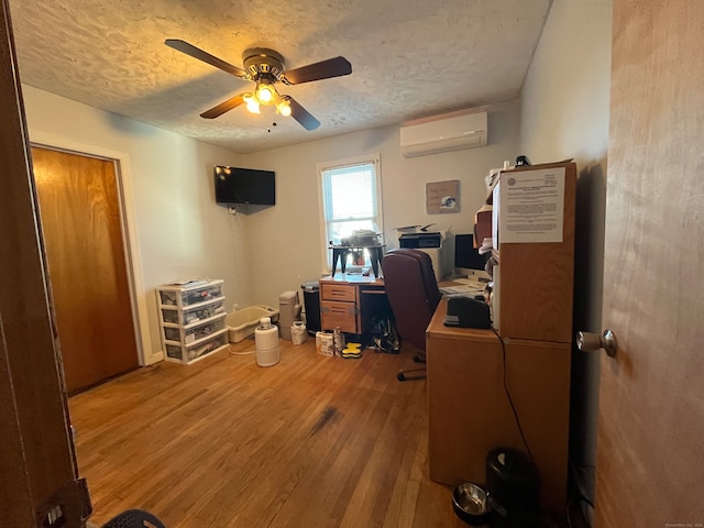 office with hardwood / wood-style floors, a wall unit AC, ceiling fan, and a textured ceiling