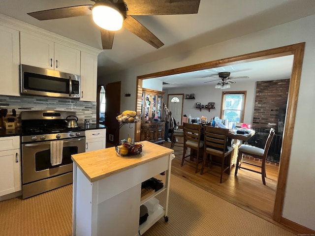 kitchen with stainless steel appliances, butcher block counters, white cabinets, decorative backsplash, and light hardwood / wood-style flooring