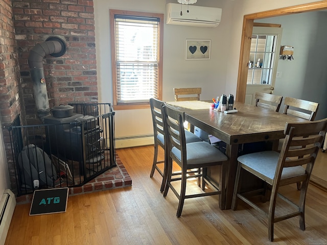 dining room featuring light hardwood / wood-style floors, baseboard heating, an AC wall unit, and a wood stove