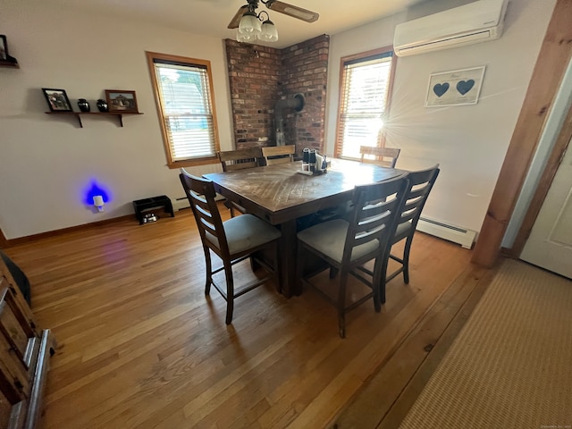 dining room with hardwood / wood-style floors, baseboard heating, a wood stove, and a wall mounted air conditioner