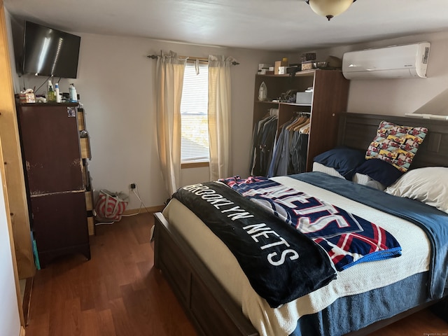 bedroom featuring dark wood-type flooring, a wall mounted AC, and a closet