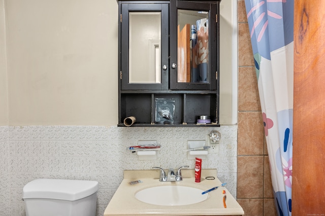 bathroom featuring tile walls, sink, a shower with shower curtain, and toilet