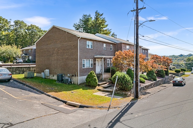 view of front of home with central air condition unit and a front lawn