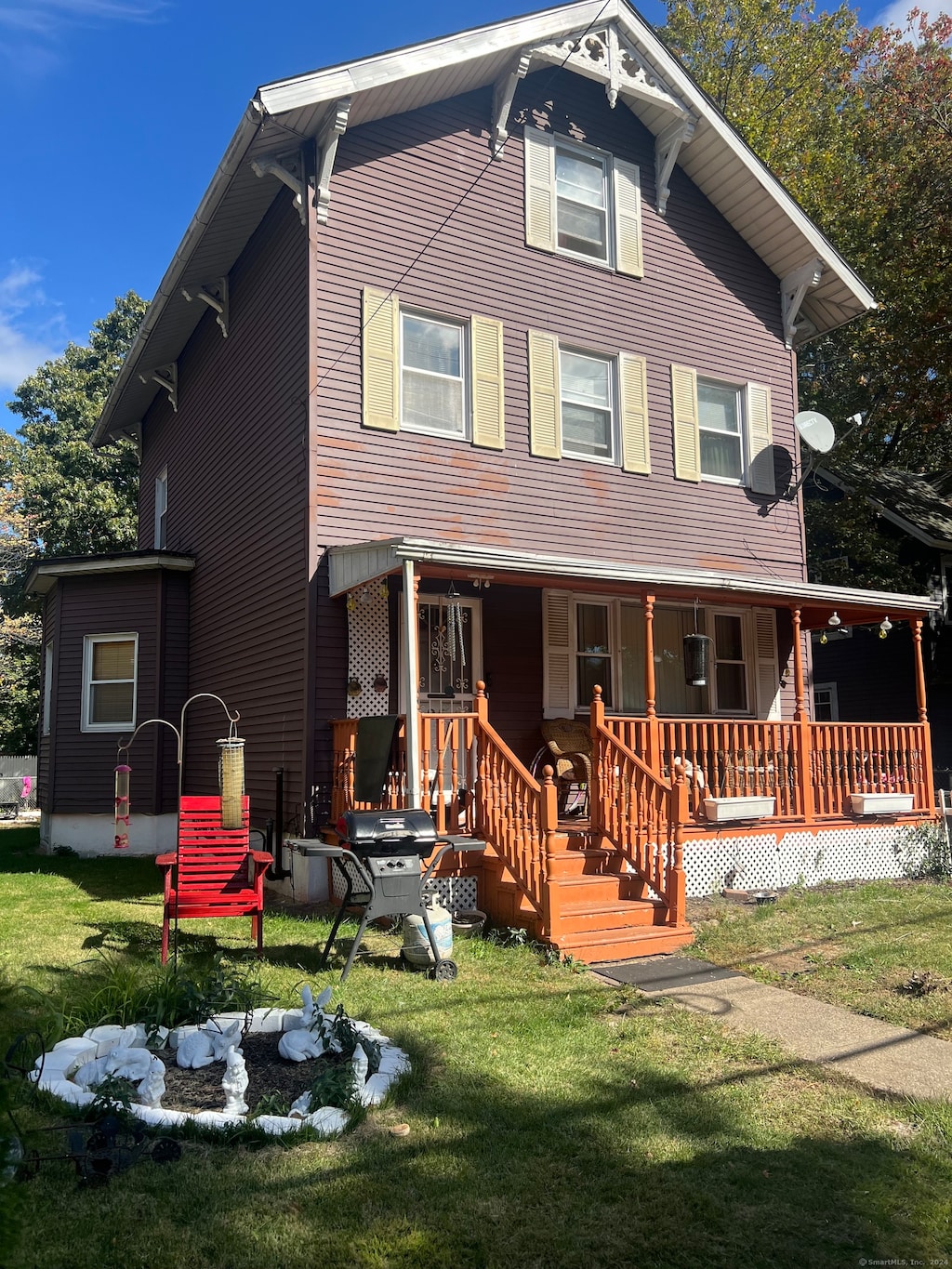 back of house featuring covered porch and a lawn