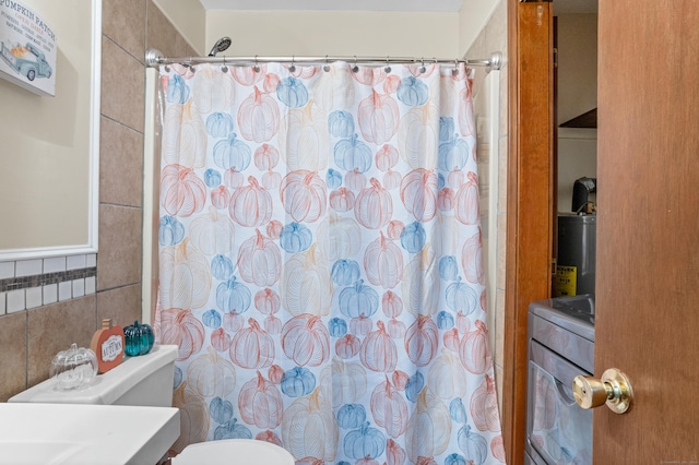 full bathroom with washer / dryer, tile walls, toilet, and a shower with curtain