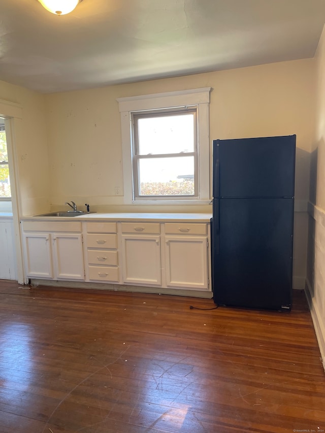 kitchen with white cabinets, black refrigerator, sink, and dark wood-type flooring